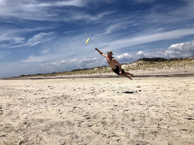 A young man jumping for a frisbee on Fire Island