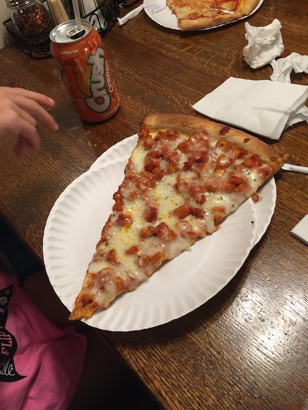slice of NY pizza on a white paper plate